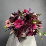 This exquisite arrangement features a captivating blend of cerise roses, gerberas, burgundy carnations, and proteas. Each bloom is carefully selected for its exceptional quality and longevity. Send a heartfelt gift that speaks volumes with this captivating bouquet.