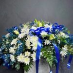 An elegant tribute featuring a cascade of white roses and lilies, accentuated by gentle hues of blue, reminiscent of the tranquil depths of the ocean.